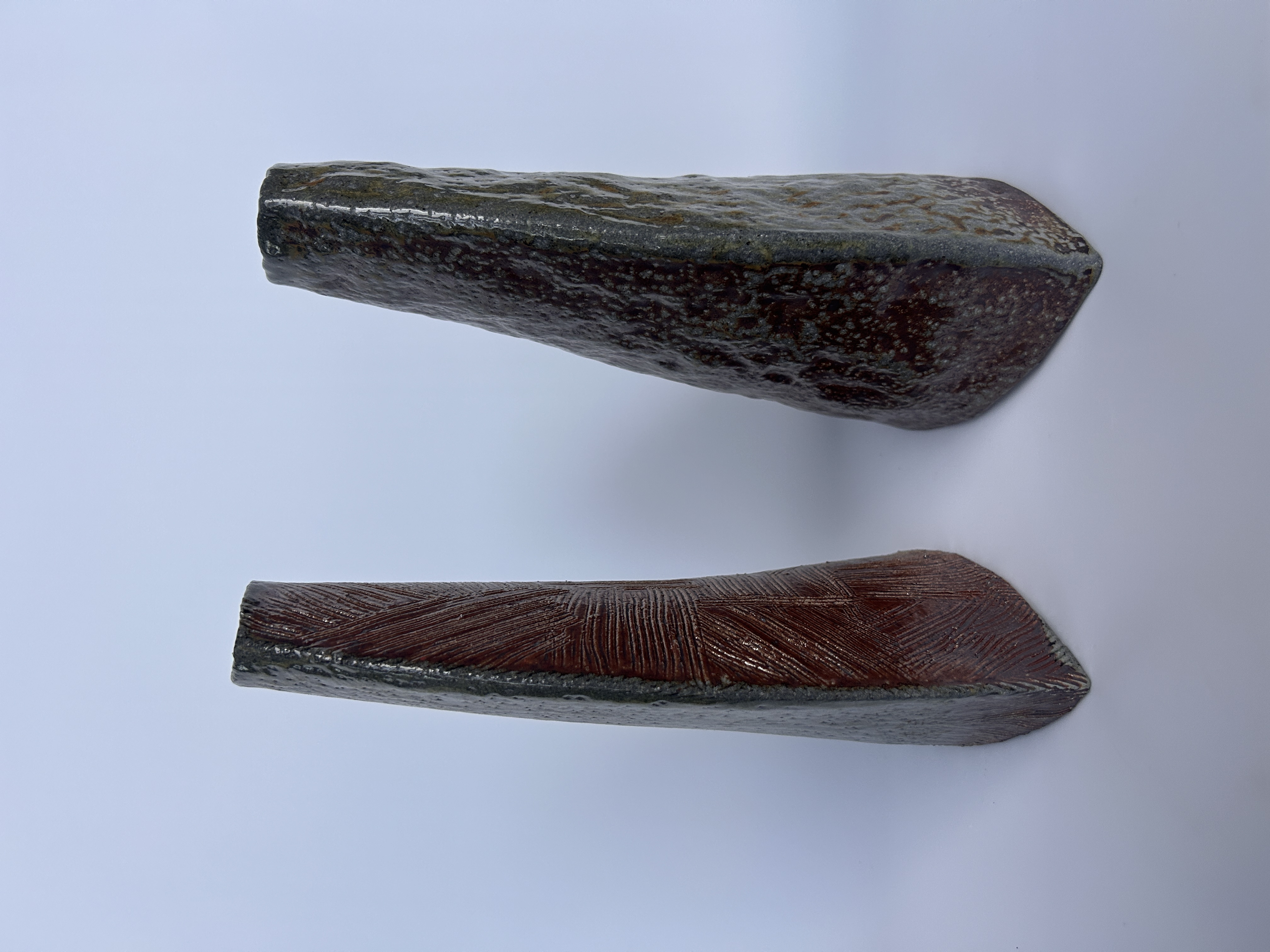 Two ceramic wedge forms with dark glaze