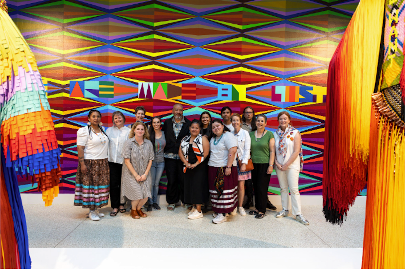 Cohort group portrait in front of Jeffrey Gibson's colorful installation